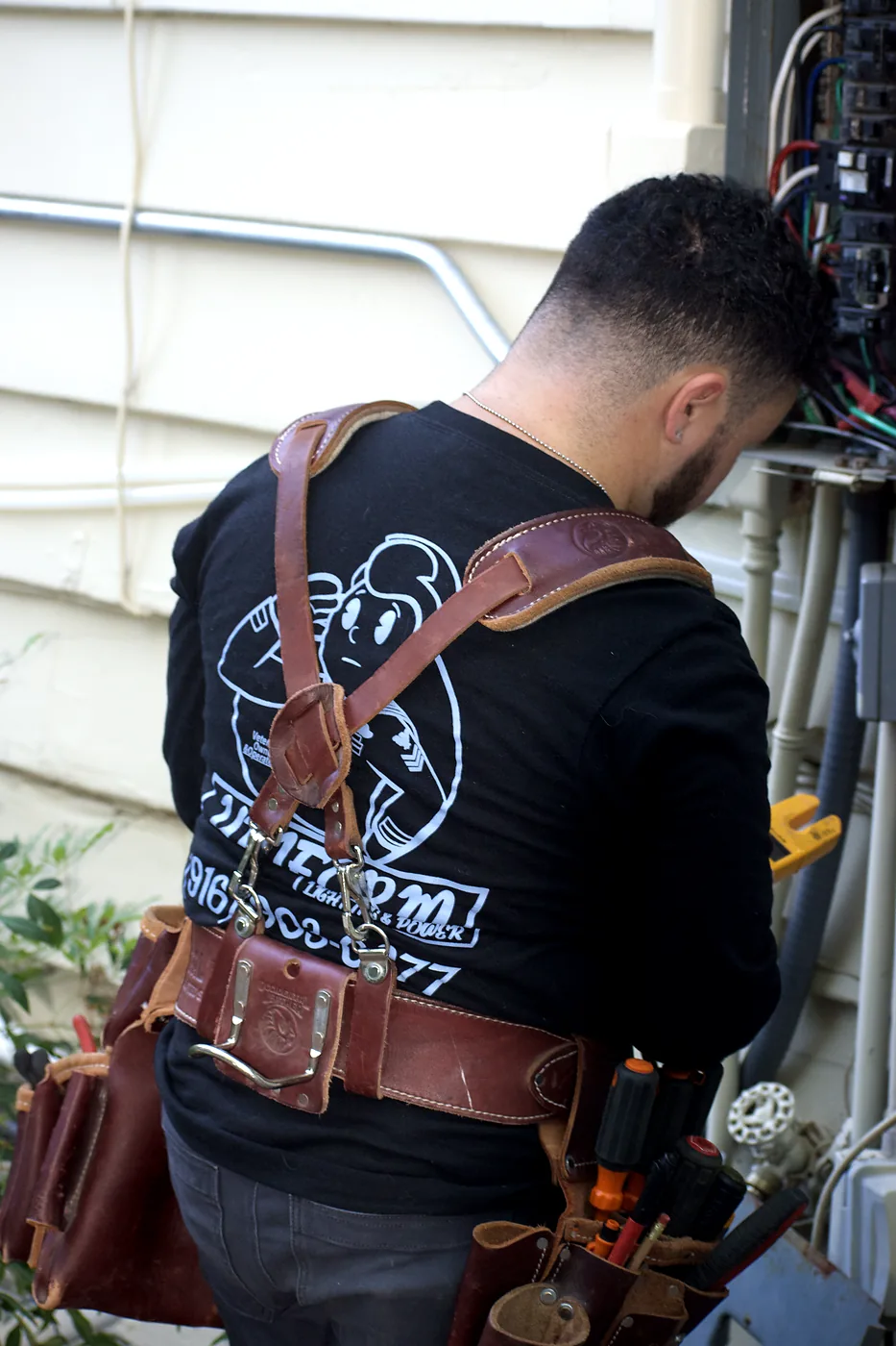 Joseph Perry performing electrical service work at an exterior electrical panel