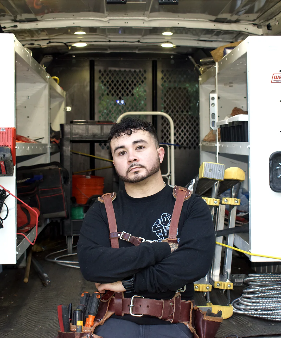 Uniform Lighting & Power electrician standing with tools inside a service van